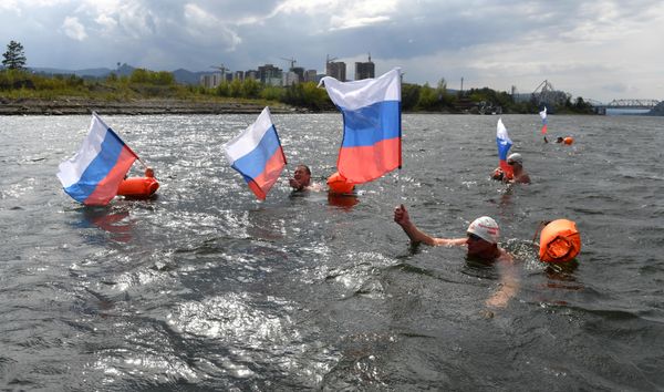 Ice swimmers during a 2,500-meter swimming marathon in Siberia's Krasnoyarsk wave Russian tricolor flags. - Sputnik International