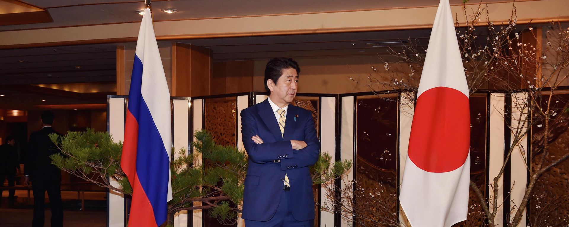 Japanese Prime Minister Shinzo Abe standing between flags of Russia, left, and Japan waits for the arrival of Russian President Vladimir Putin at a hot springs resort for their meeting in Nagato, Japan, Thursday, Dec. 15, 2016 - Sputnik International, 1920, 11.02.2023