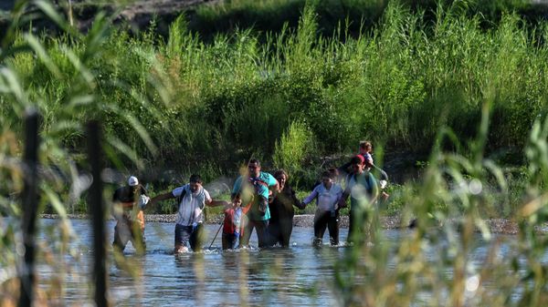 A migrant family from Venezuela illegally crosses the Rio Grande River in Eagle Pass, Texas, at the border with Mexico on June 30, 2022.  - Sputnik International