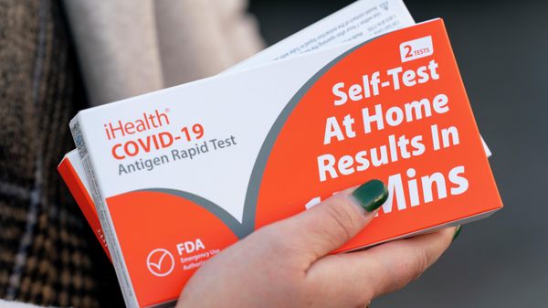 A woman holds two boxes of at-home Covid-19 test kits after waiting in a long line that snakes multiple times around the Shaw Library in Washington, Wednesday, Dec. 22, 2021 - Sputnik International