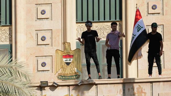 A supporter of Shiite cleric Muqtada al-Sadr waves a national flag from the roof of the Government Palace during a demonstration in Baghdad, Iraq, Monday, Aug. 29, 2022 - Sputnik International
