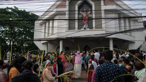 A man, center, wearing mask as a precaution against COVID-19 gestures to devotees to make way for an arriving procession as Christians observe Palm Sunday outside a Church in Kochi, Kerala state, India, Sunday, April 10, 2022. - Sputnik International
