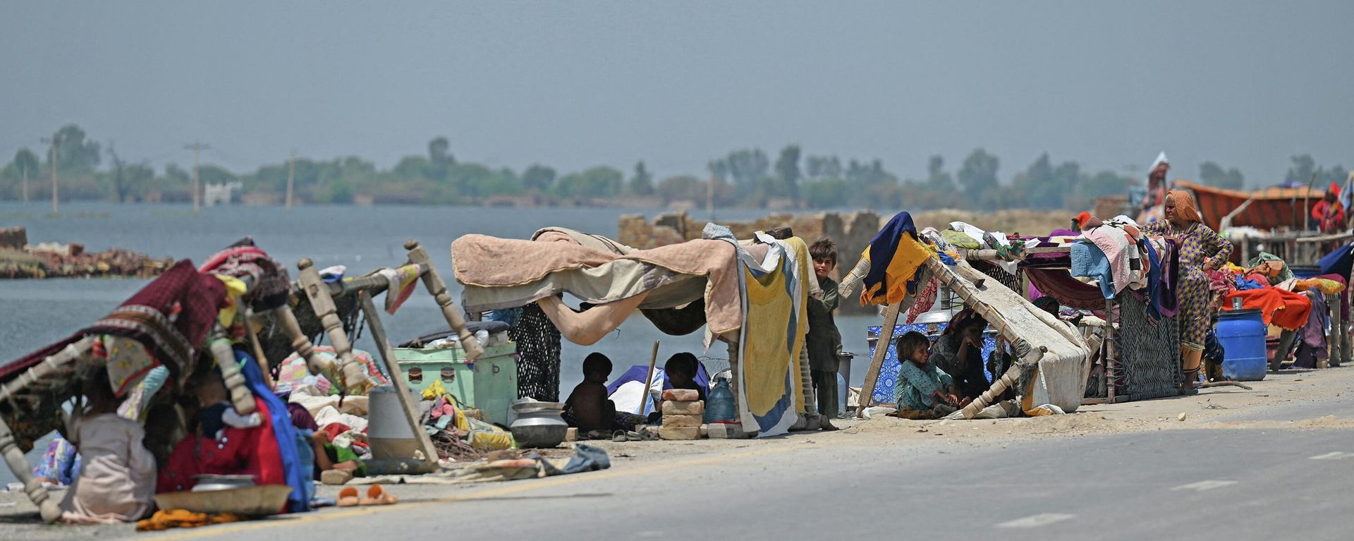 Internally displaced flood-affected people shelter in makeshift tents along a road in higher ground in flooded area after heavy monsoon rains on the outskirts of Jacobabad, Sindh province, on September 6, 2022 - Sputnik International, 1920, 06.09.2022