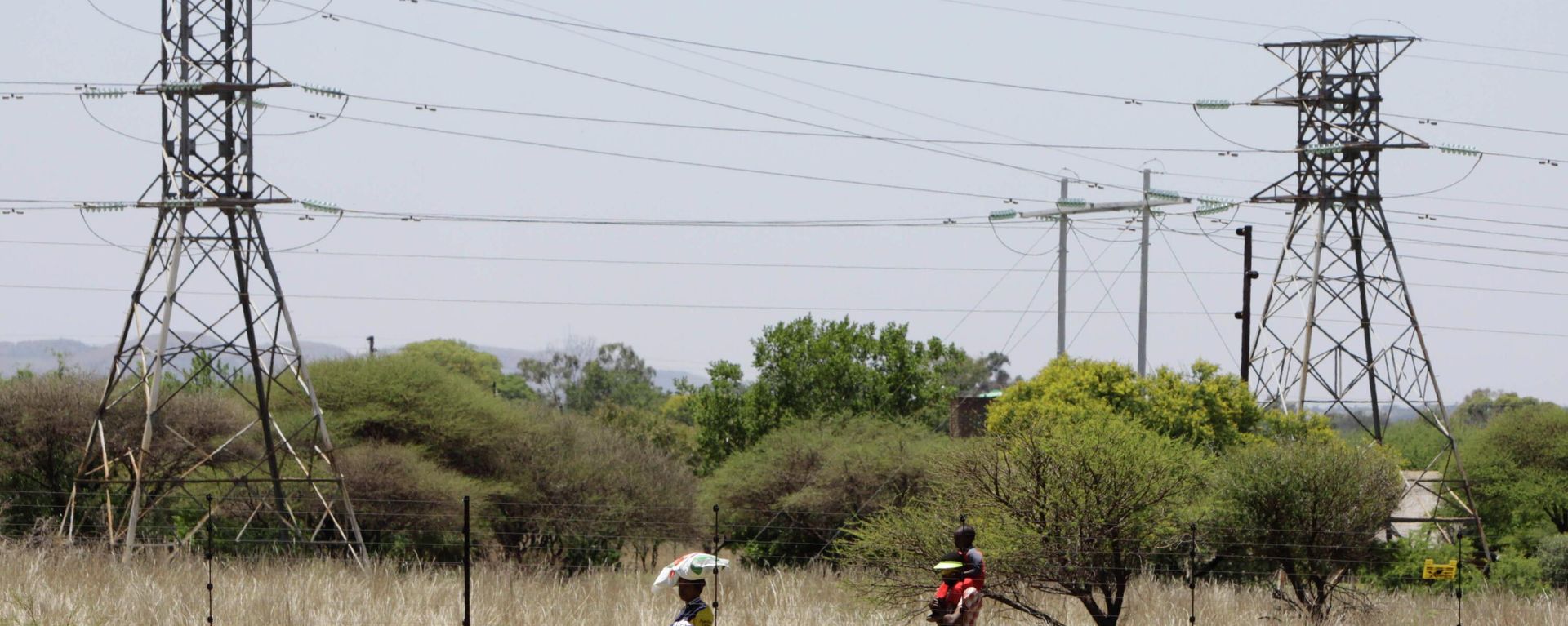 People walk below power pylons at Hartebeespoort, South Africa, Friday Nov. 25, 2011. Eskom is Africa's biggest power utility, accounting for more than 60 percent of all the electricity generated on the continent, according to the World Bank. It also exports across southern Africa. Critics and even supporters say Eskom should have started its move toward renewable sources of energy earlier, and now needs to set its ambitions higher. (AP Photo/Denis Farrell) People walk below power pylons at Hartebeespoort, South Africa, Friday Nov. 25, 2011. Eskom is Africa's biggest power utility, accounting for more than 60 percent of all the electricity generated on the continent, according to the World Bank. It also exports across southern Africa. Critics and even supporters say Eskom should have started its move toward renewable sources of energy earlier, and now needs to set its ambitions higher. (AP Photo/Denis Farrell) - Sputnik International, 1920, 11.09.2022