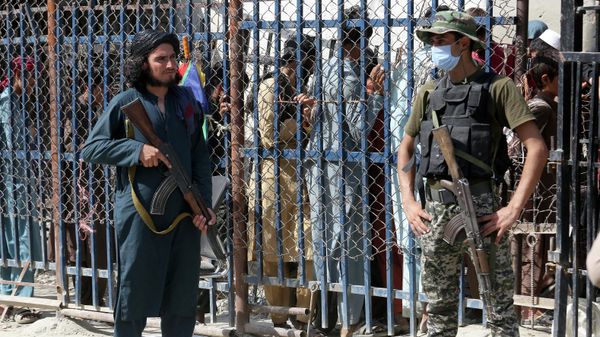 A Pakistani paramilitary soldier, right, and a Taliban fighter stand guard on their respective sides at a border crossing point between Pakistan and Afghanistan in Torkham, in the Khyber district of Pakistan, Aug. 21, 2021 - Sputnik International