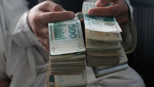 An Afghan money changer holds Pakistani currency bundles at the money exchange market in Kandahar south of Kabul, Afghanistan, Sunday, Aug. 7, 2016. - Sputnik International