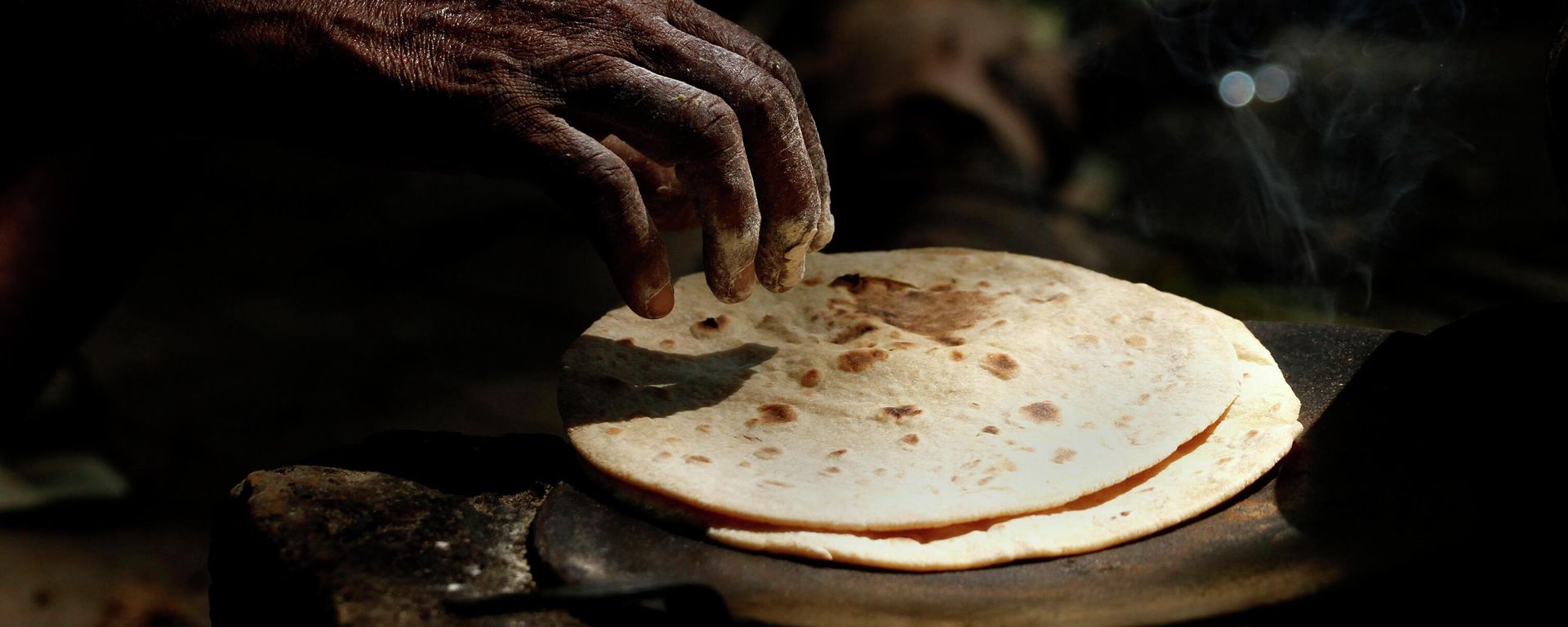 An Indian woman cooks chapati, or Indian bread, on a roadside in Allahabad, India, Friday, July 5, 2013. An Indian woman cooks chapati, or Indian bread, on a roadside in Allahabad, India, Friday, July 5, 2013. - Sputnik International, 1920, 20.09.2022