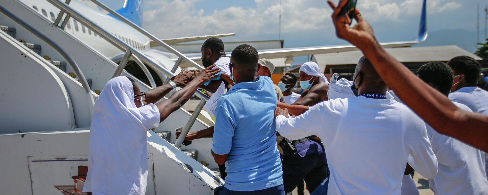 FILE - In this Sept. 21, 2021, file photo, Haitians deported from the United States try to board the same plane in which they were deported, in an attempt to return to the United States, on the tarmac of the Toussaint Louverture airport in Port-au-Prince, Haiti. The Border Patrol's treatment of Haitian migrants, they say, is just the latest in a long history of discriminatory U.S. policies and of indignities faced by Black people, sparking new anger among Haitian Americans, Black immigrant advocates and civil rights leaders.(AP Photo/Odelyn Joseph, File) - Sputnik International, 1920, 20.09.2022