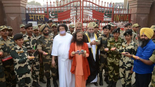 All India Imam Organization Chief Imam, Imam Umer Ahmed Ilyasi (5R), the Parmarth Niketan Ashram in Rishikesh, President and spiritual head  H.H. Swami Chidanand Saraswatiji (C), the founder of Ahimisa Vishwa Bharti and eminent Jain, Acharya Lokesh Muni (5L), Indian Border Security Force (BSF) Deputy Inspector General JS Oberoi (4L), BSF Commandant Sudeep (4R) and Indian Border Security Force (BSF) personnel pose with earthen lamps on the eve of the Diwali festival at the India-Pakistan Wagah Border on October 29, 2016. - Sputnik International