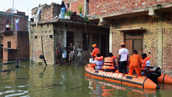 India's National Disaster Response Force (NDRF) personnel distribute food and relief materials to people in flooded areas following heavy monsoon rains that caused the overflowing of the Ganges and Yamuna rivers in Allahabad on August 27, 2022. - Sputnik International