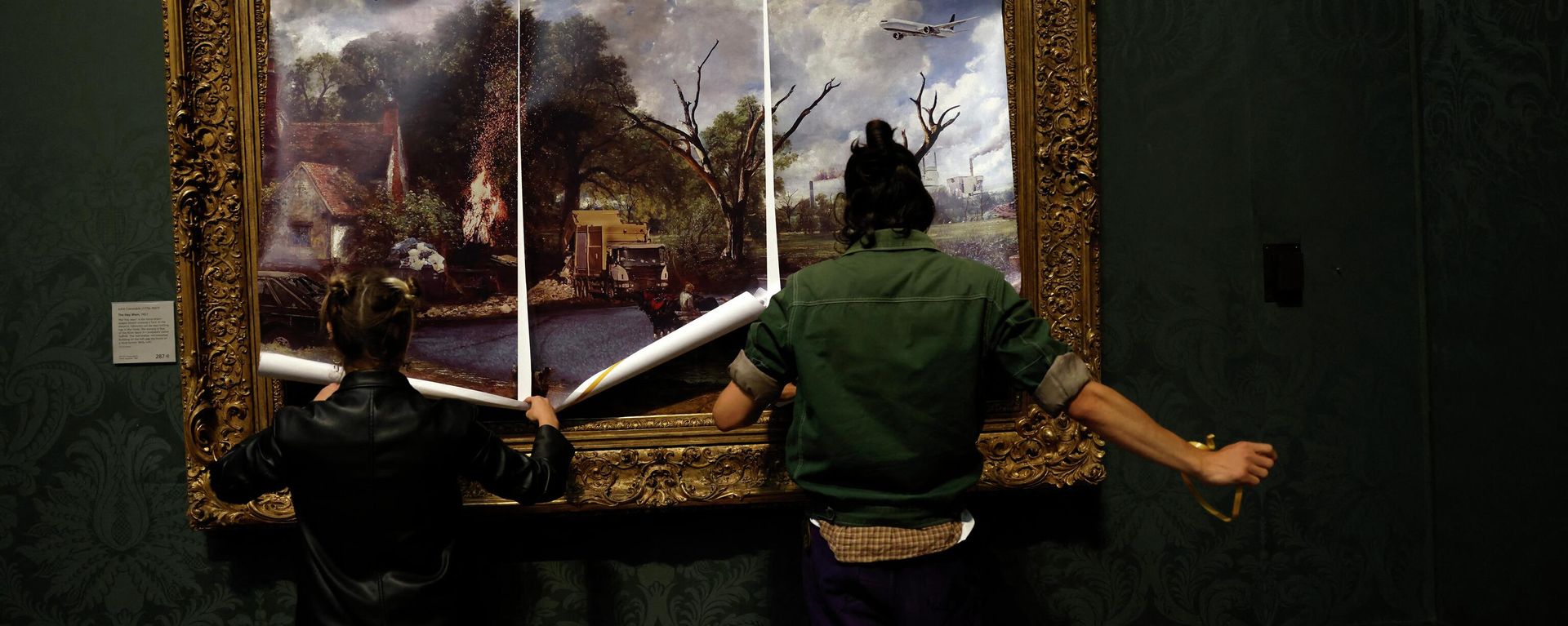Activists from the 'Just Stop Oil' campaign group cover 'The Hay Wain' painting by English artist John Constable, in a mock 'undated' version including roads and aircraft, before glueing their hands to the frame in protest against the use of fossil fuels, in the National Gallery in London on July 4, 2022. - Sputnik International, 1920, 29.10.2022