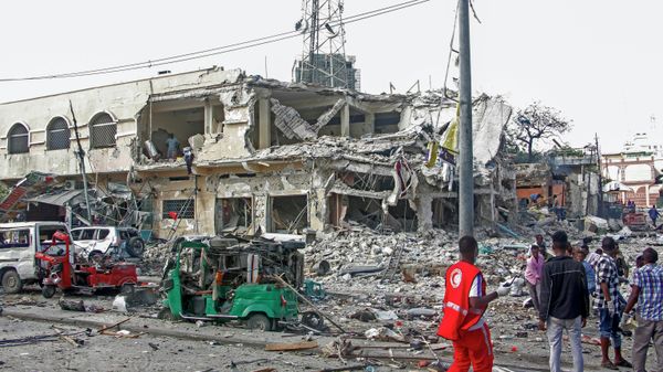 People observe a destroyed building and vehicles at the scene of a two car bombs attack in Mogadishu, Somalia, Saturday Oct. 29, 2022. Two car bombs exploded Saturday at a busy junction in Somalia's capital near key government offices, leaving scores of civilian casualties, police told state media. - Sputnik International