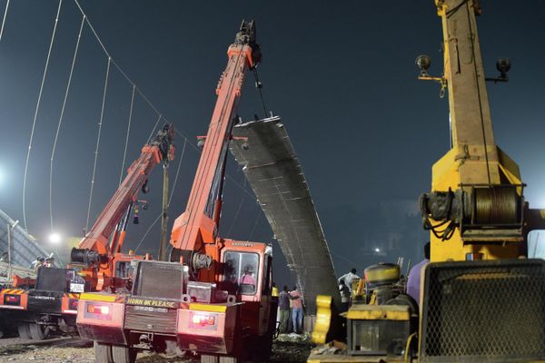 Workers remove a section of a suspension bridge (C) after the structure across the Machchhu River collapsed in Morbi, some 220 km from Ahmedabad, early on October 31, 2022. - At least 75 people were killed on October 30 in India after an almost 150-year-old colonial-era pedestrian bridge collapsed, sending scores of people tumbling into the river below. - Sputnik International