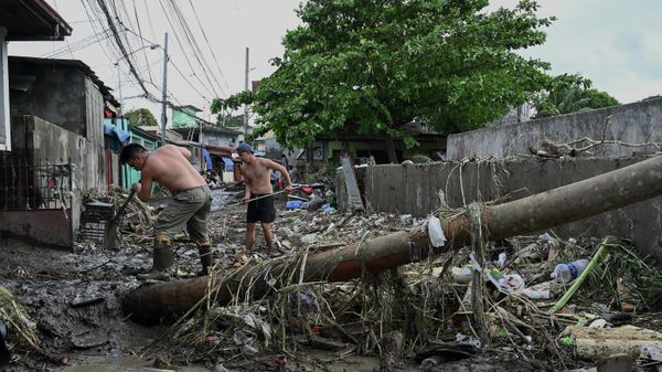 Men clean the debris along a debris-covered street in Noveleta, Cavite province on October 30, 2022, a day after Tropical Storm Nalgae hit. - - Sputnik International