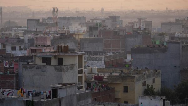 A man stands on a terrace of a building as morning haze envelops the skyline in New Delhi, India, Tuesday, Oct. 25, 2022. - Sputnik International