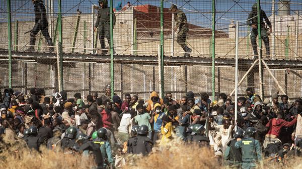 Riot police officers cordon off the area after migrants arrive on Spanish soil and crossing the fences separating the Spanish enclave of Melilla from Morocco in Melilla, Spain, on June 24, 2022.  - Sputnik International
