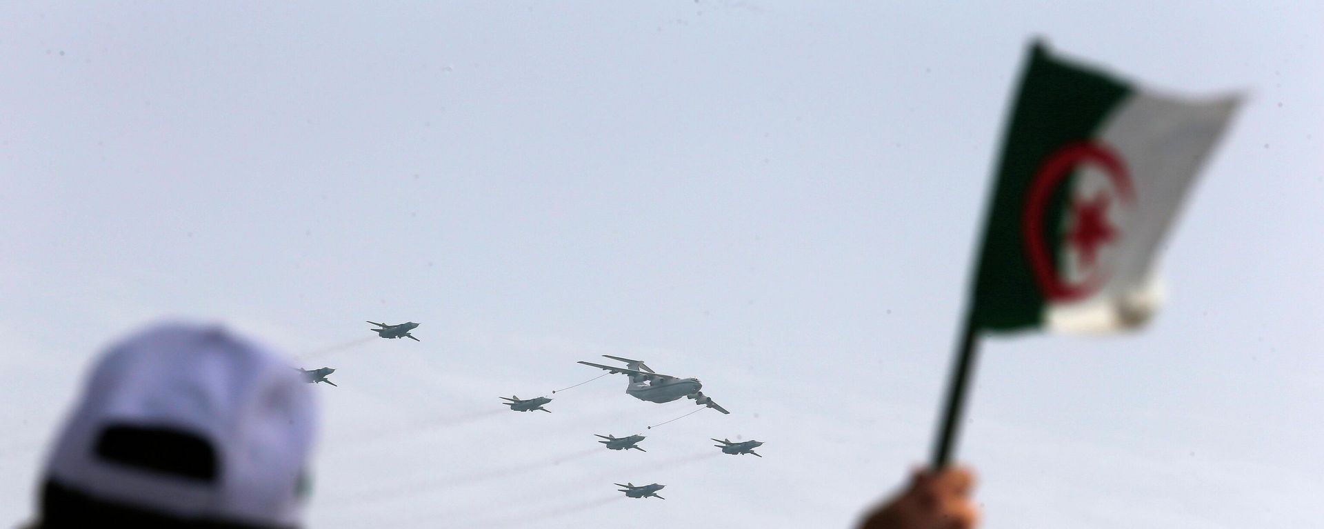 A man waves an Algerian flag as war planes fly during a military parade to mark the 60th anniversary of Algeria's independence, Tuesday, July 5, 2022 in Algiers.  - Sputnik International, 1920, 02.11.2022
