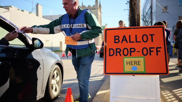 An official ballot collector for the Cuyahoga County Board of Elections gives a voter their I Voted sticker after depositing their mail-in ballots into a collection box in Cleveland, Ohio on November 6, 2022, ahead of the midterm elections - Sputnik International