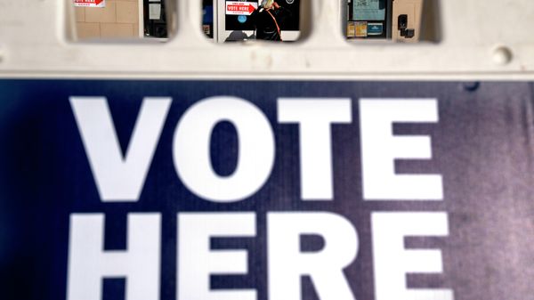 A woman is seen through a vote here sign, as she enters a polling site to vote in the midterm elections, Tuesday, Nov. 8, 2022, in Washington.  - Sputnik International