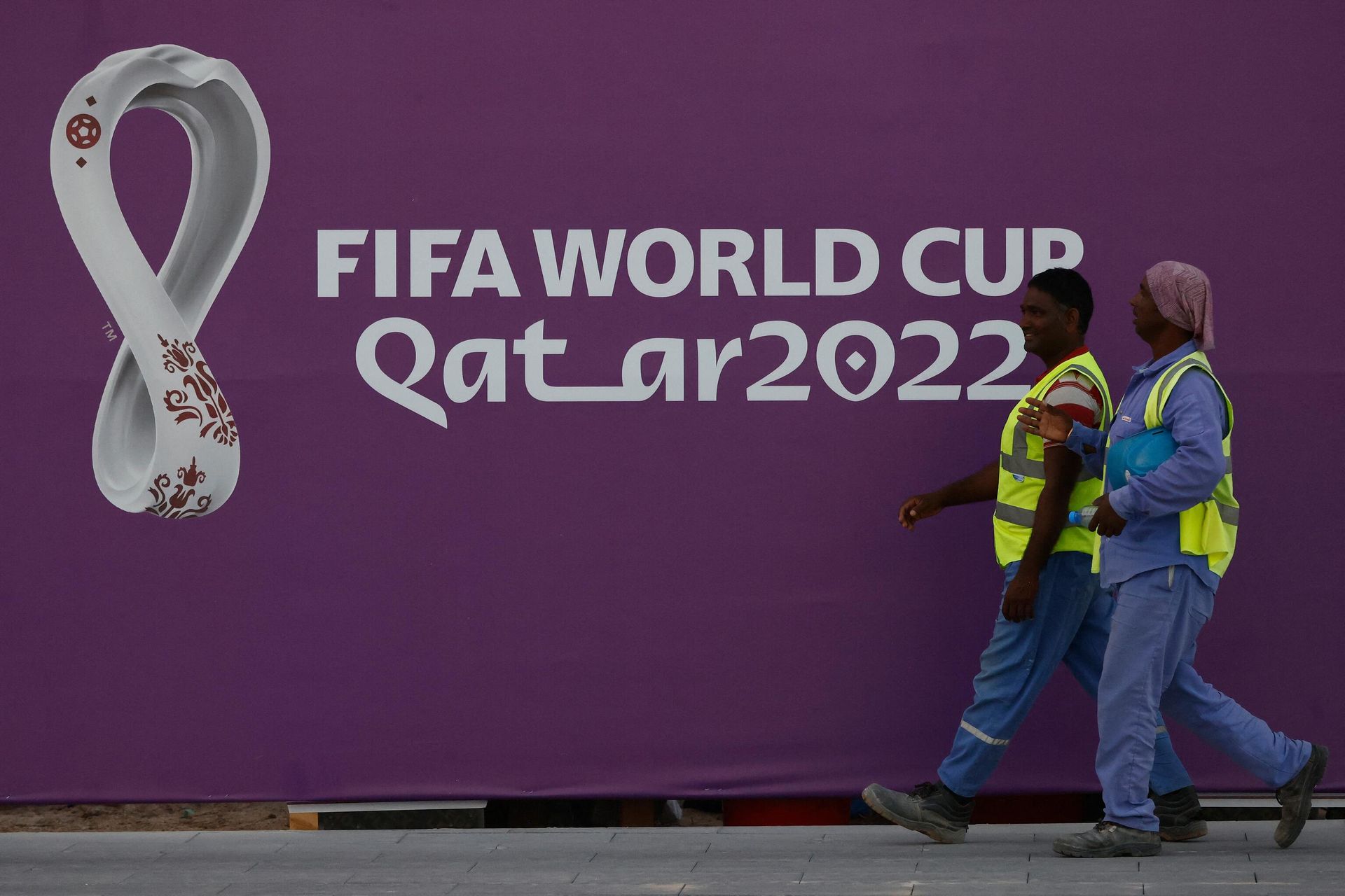Workers walk past a FIFA World Cup sign in Doha on November 16, 2022, ahead of the Qatar 2022 World Cup football tournament. Workers walk past a FIFA World Cup sign in Doha on November 16, 2022, ahead of the Qatar 2022 World Cup football tournament. - Sputnik International, 1920, 17.11.2022