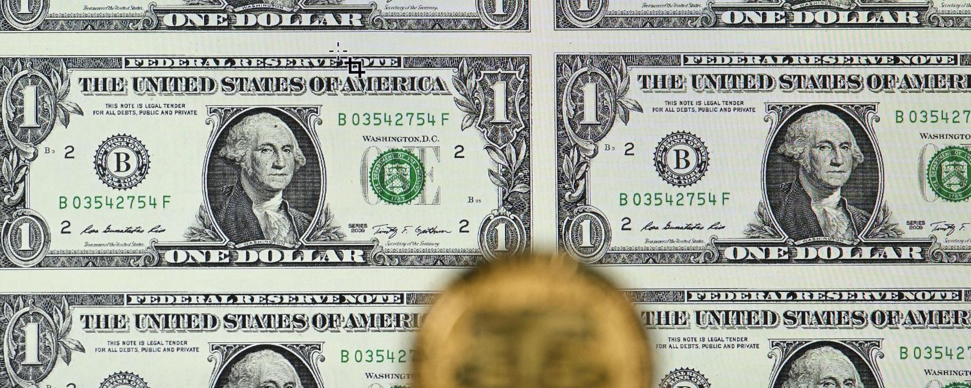 An illustration picture taken in London on May 8, 2022, shows a gold plated souvenir cryptocurrency Tether (USDT) coin arranged beside a screen displaying US dollar notes. - Tether (USDT) is an Ethereum token known as a stablecoin that is pegged to the value of the US dollar, and is currently the largest stablecoin with a market value of USD 83 billion dollars.  - Sputnik International, 1920, 09.06.2023