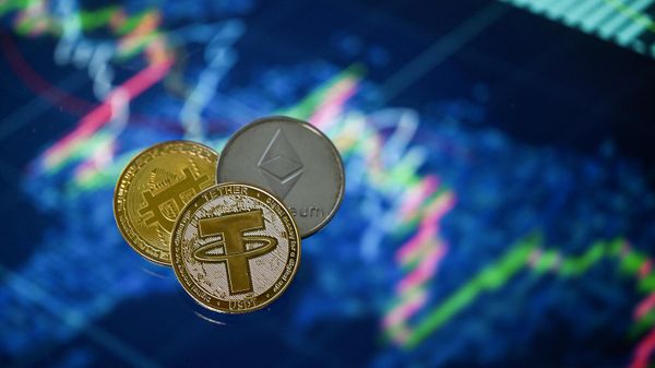 An illustration picture taken in London on May 8, 2022, shows gold plated souvenir cryptocurrency Tether (USDT), Bitcoin and Etherium coins arranged beside a screen displaying a trading chart. - Sputnik International