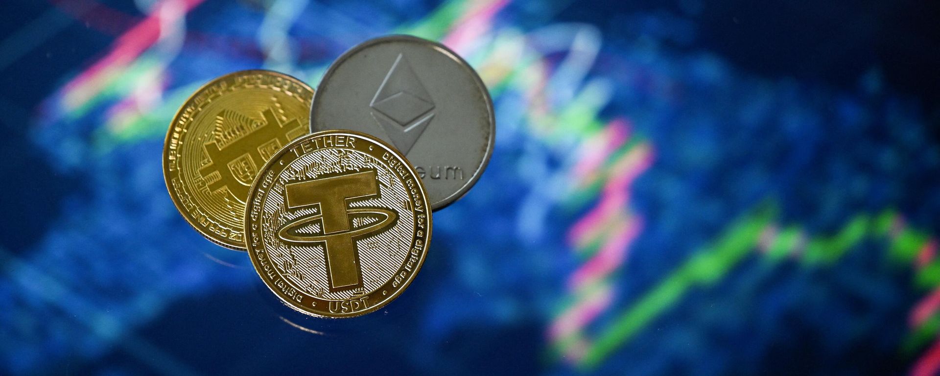 An illustration picture taken in London on May 8, 2022, shows gold plated souvenir cryptocurrency Tether (USDT), Bitcoin and Etherium coins arranged beside a screen displaying a trading chart. An illustration picture taken in London on May 8, 2022, shows gold plated souvenir cryptocurrency Tether (USDT), Bitcoin and Etherium coins arranged beside a screen displaying a trading chart. - Sputnik International, 1920, 13.12.2022