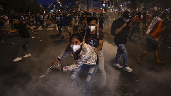 Supporters of former President Pedro Castillo take cover from tear gas thrown by the police during clashes on a demonstration demanding his release and the closure of the Peruvian Congress in Lima, on December 11, 2022. - Sputnik International