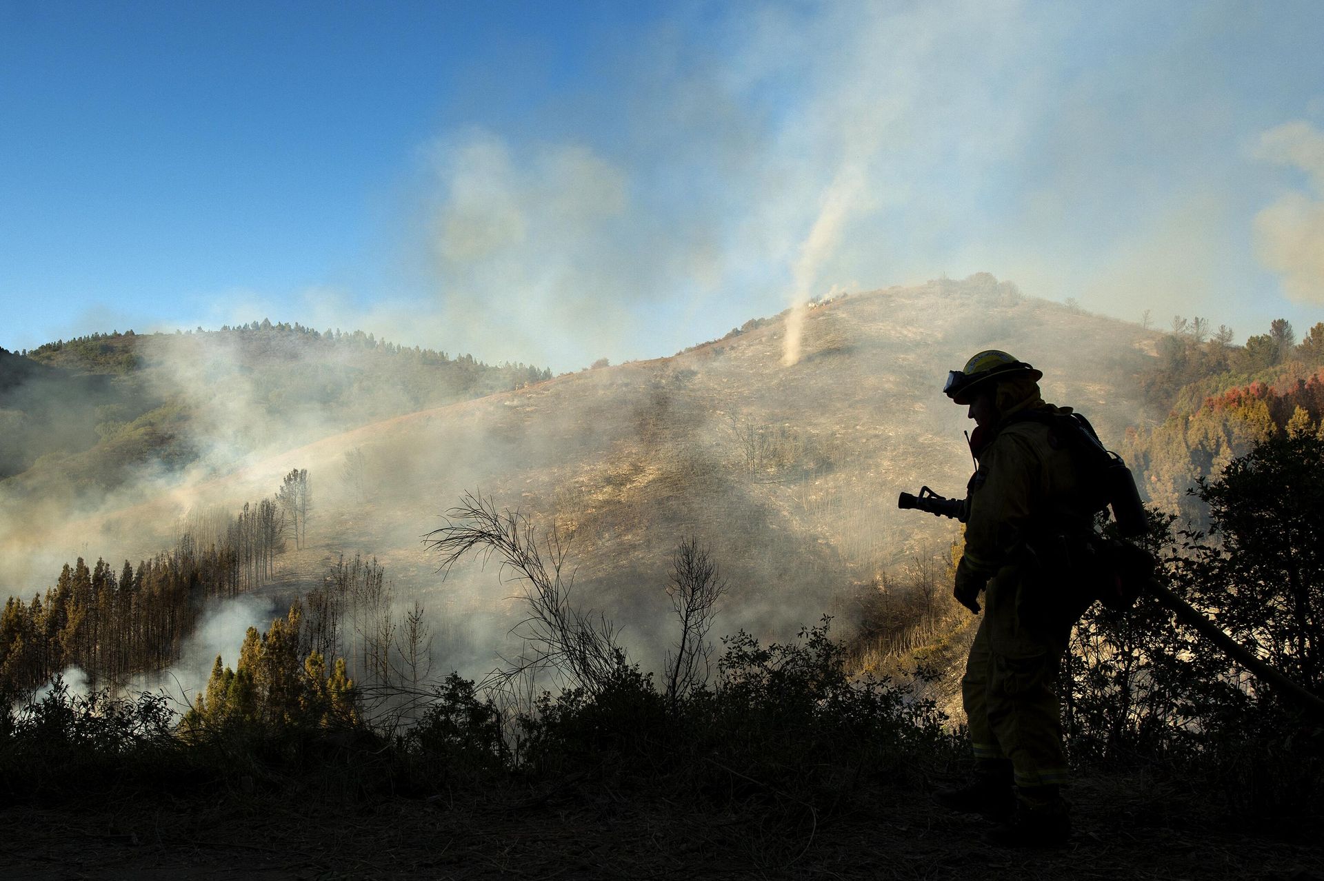 A firefighter walks with a hose as a dust devil kicks up along a charred hillside in the Santa Cruz Mountains near Morgan Hill, California on September 27, 2016.  - Sputnik International, 1920, 14.12.2022