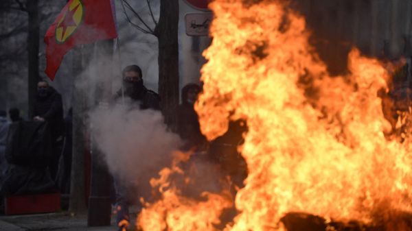 A protester holds a Kurdish workers party (PKK) flag behind a fire during clashes following a demonstration of supporters and members of the Kurdish community, a day after a gunman opened fire at a Kurdish cultural centre killing three people, at The Place de la Republique in Paris on December 24, 2022 - Sputnik International