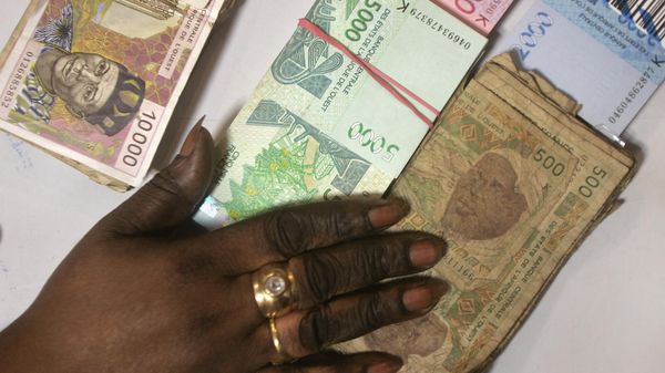 A bank teller counts piles of new West African CFA Franc banknotes plus old-style  500 CFA notes, bottom-right, and old-style 10,000 CFA notes, top-left, at a bank in Dakar, Senegal Monday, Sept. 13, 2004. French West Africa is engaged in a massive, eight-country campaign to retire more than 1 billion euros (dollars) in aged, limp currency. - Sputnik International