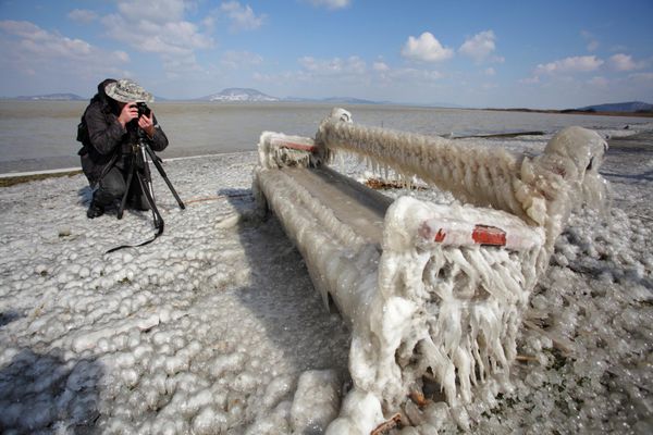 An ice covered bench is photographed by a man on the shore of Lake Balaton in Balatonfenyves, 155km south-west of Budapest, Hungary on Saturday 16 March 2013, after water blown by high winds froze while dripping off in sub-zero temperatures. - Sputnik International