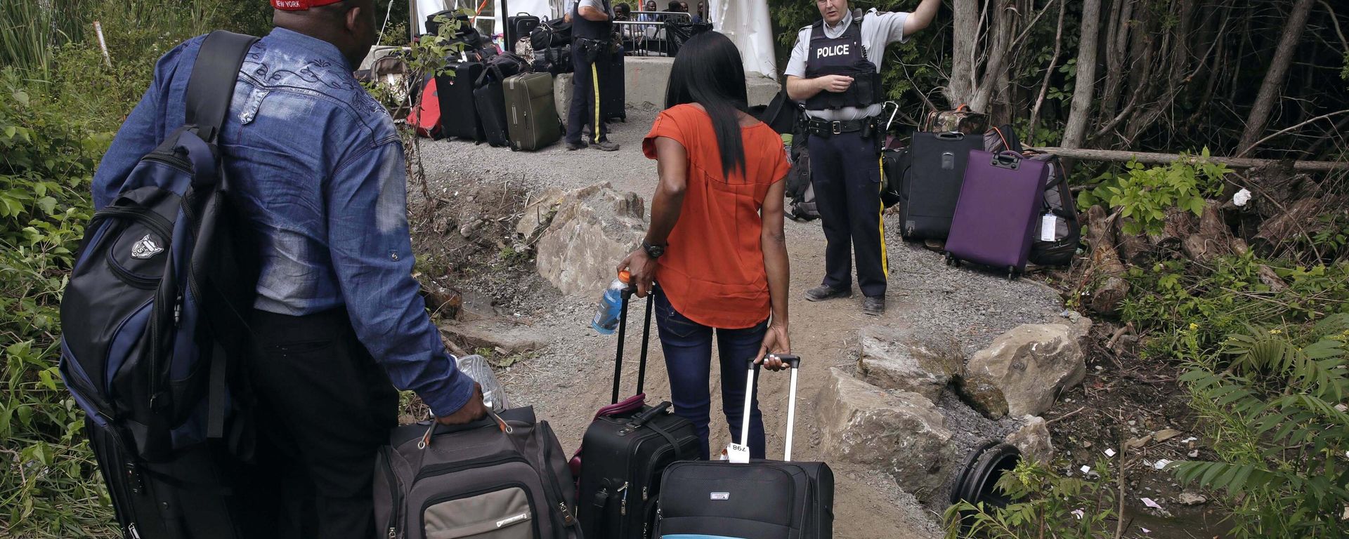 FILE - In this Aug. 7, 2017 file photo, a Royal Canadian Mounted Police officer informs a migrant couple of the location of a legal border station, shortly before they illegally crossed from Champlain, N.Y., to Saint-Bernard-de-Lacolle, Quebec, using Roxham Road. In the first nine months of 2022, the Immigration and Refugee Board of Canada finalized more than 2,700 claims by Mexican asylum seekers. Of those, 1,032 were accepted, 1,256 were rejected; and the remaining 400-plus were either abandoned, withdrawn, or had other outcomes, said Christian Tessier, an IRB spokesperson.  - Sputnik International, 1920, 12.05.2023
