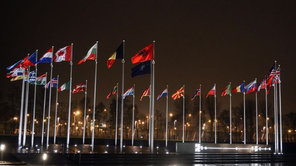 The picture shows the flags of the participating countries raised in front of the headquarters of the North Atlantic Treaty Organization (NATO - Sputnik International