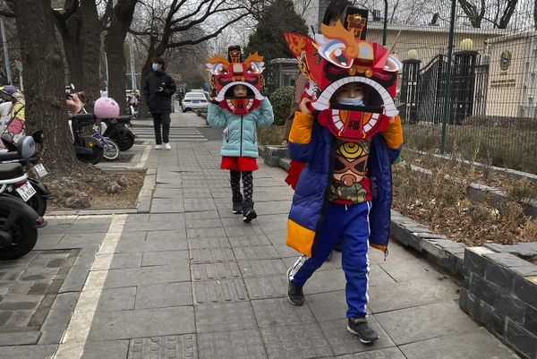 Children wearing cardboard lion dance masks walk along a street in Beijing. The lion dance is a traditional part of celebrations as well as the dragon dance, performed by professionals. - Sputnik International