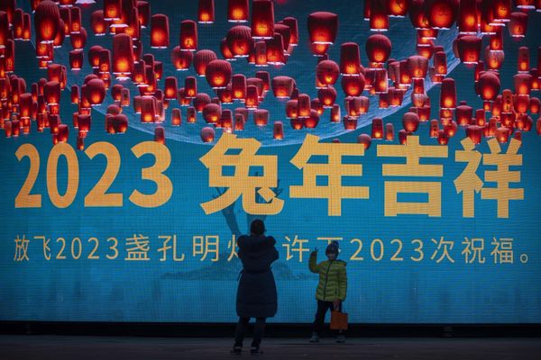 A boy wearing a face mask poses in front of a large screen displaying a graphic decoration for the upcoming Lunar New Year in Beijing.  - Sputnik International