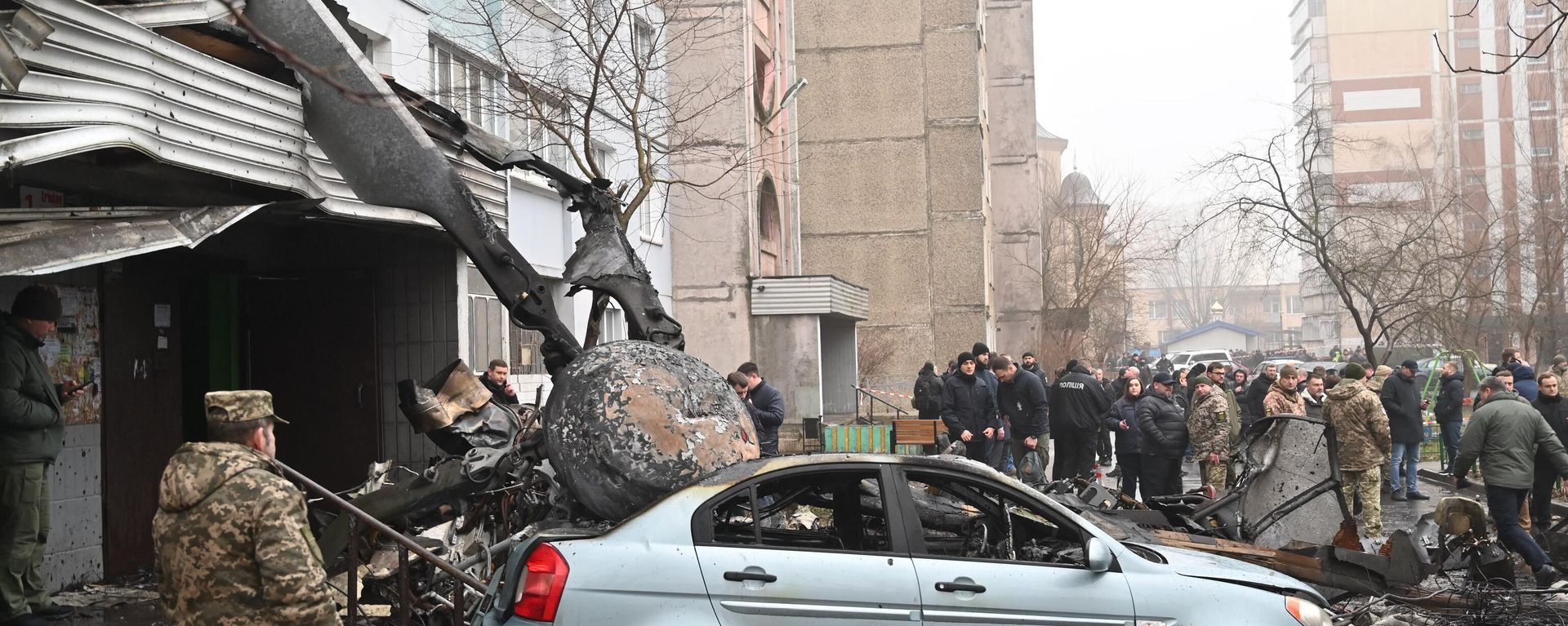 Military and onlookers stand at the site where a helicopter crashed near a kindergarten outside the capital Kiev, killing sixteen people, including two children and Ukrainian interior minister, on January 18, 2023. Military and onlookers stand at the site where a helicopter crashed near a kindergarten outside the capital Kiev, killing sixteen people, including two children and Ukrainian interior minister, on January 18, 2023. - Sputnik International, 1920, 18.01.2023