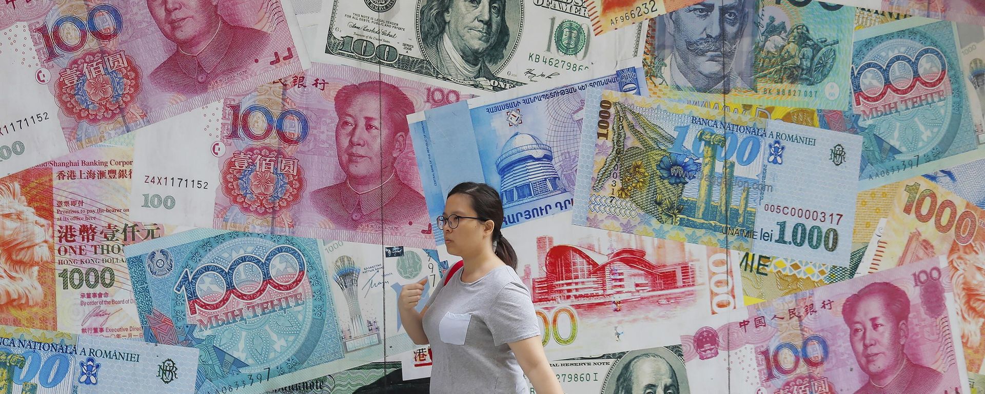 A woman walks by a money exchange shop decorated with banknotes of Chinese yuan and US dollars at Central, a business district in Hong Kong, Tuesday, Aug. 6, 2019. - Sputnik International, 1920, 01.07.2023