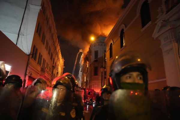 Police in riot gear block a street as a building burns behind them after a day a day of clashes with anti-government protesters in Lima, Peru, Thursday, January 19, 2023.  - Sputnik International