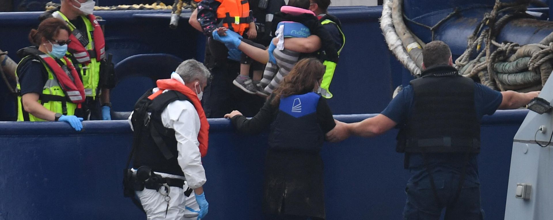 UK Border Force officials carry children intercepted whilst travelling in a RIB from France to England from their patrol vessel HMC Eagle after arriving at the Marina in Dover, southeast England on August 14, 2020 UK Border Force officials carry children intercepted whilst travelling in a RIB from France to England from their patrol vessel HMC Eagle after arriving at the Marina in Dover, southeast England on August 14, 2020 - Sputnik International, 1920, 26.01.2023
