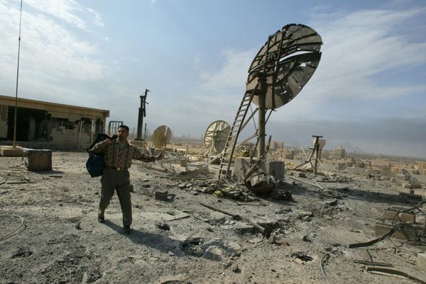 An employee of the Iraqi Ministry of Information makes his way between wrecked dishes on the roof of the ministry's building in Baghdad March 29, 2003, after it was hit by a coalition missile overnight. Waves of attacks on the Iraqi capital and its surrounds continued on the 10th day of the war, with at least one missile crashing into the Information Ministry after scores of people died in a market.   AFP PHOTO/Patrick BAZ (Photo by PATRICK BAZ / AFP) - Sputnik International