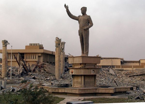A statue of Iraqi President Saddam Hussein stands in the middle of the ruins of the Iraqi Air Force headquarters as the sun sets in Baghdad April 9, 2003. US tanks and troops poured into Baghdad as the Iraqi leader's government was overthrown after a three-week onslaught by US-led forces. AFP PHOTO/RAMZI HAIDAR (Photo by RAMZI HAIDAR / AFP) - Sputnik International