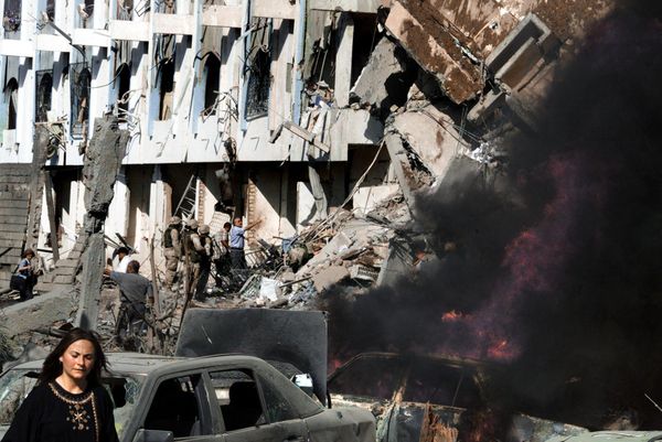 A woman walks past burning cars in front of the heavily damaged United Nations headquarters at the Canal Hotel in eastern Baghdad after a huge explosion rocked the building leaving several people dead August 19, 2003. UN special representative for Iraq Sergio Vieira de Mello was wounded in the apparent truck bomb attack, UN officials in New York said. - Sputnik International