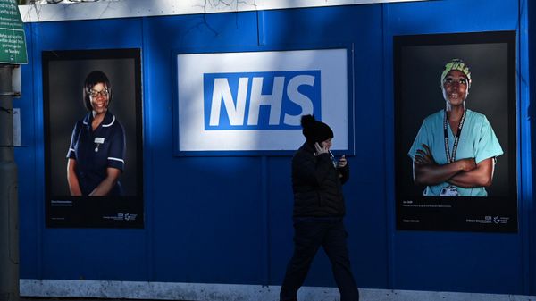 Pedestrians walk past images of workers of Britain's National Health Service, south London, January 5, 2022 - Sputnik International