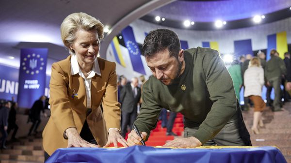 Ukrainian President Volodymyr Zelenskyy, right, and European Commission President Ursula von der Leyen write their wishes on a Ukrainian flag during the EU-Ukraine summit in Kyiv - Sputnik International