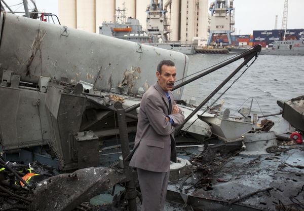 In this photo taken on 20 May 2011, a Libyan official inspects damage on ships moored at the seaport in Tripoli, Libya. NATO fighter jets struck three ports in bombing runs overnight, targeting Gadhafi's navy. - Sputnik International