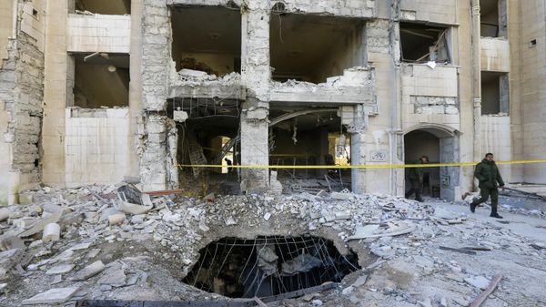 Syrian security forces members inspect a building damaged in a reported Israeli missile strike in Damascus on February 19, 2023 - Sputnik International