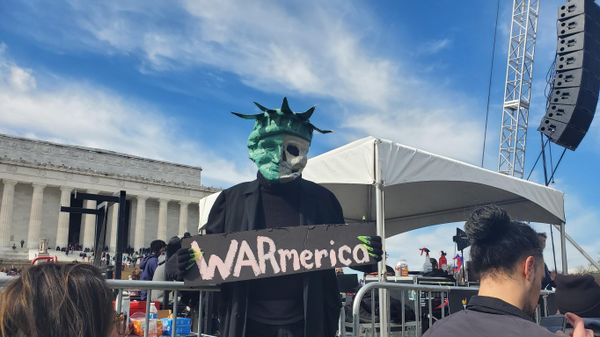 A protester holds a sign saying WARmerica at the Rage Against the War Machine Rally in Washington DC on February 19, 2023 - Sputnik International