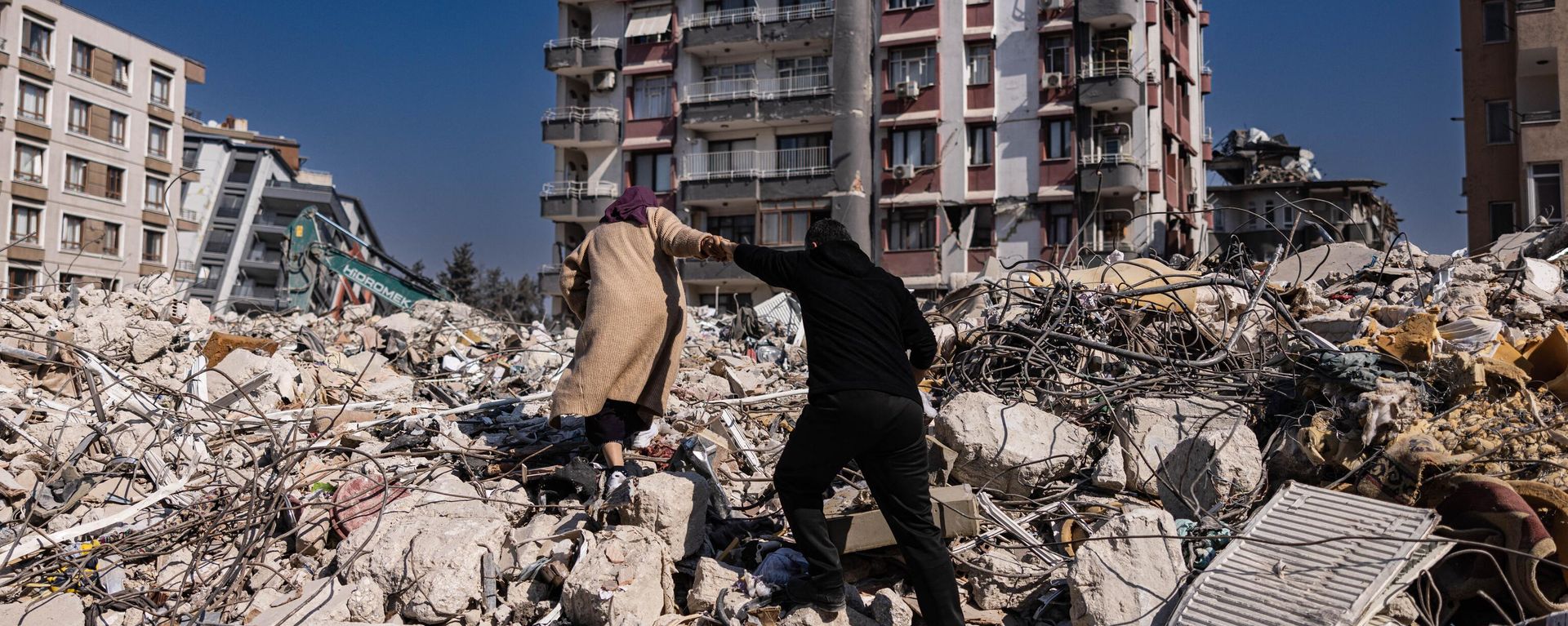 A couple climbs the rubble of collapsed buildings in Antakya, southern Turkey on February 20, 2023. A couple climbs the rubble of collapsed buildings in Antakya, southern Turkey on February 20, 2023. - Sputnik International, 1920, 21.02.2023