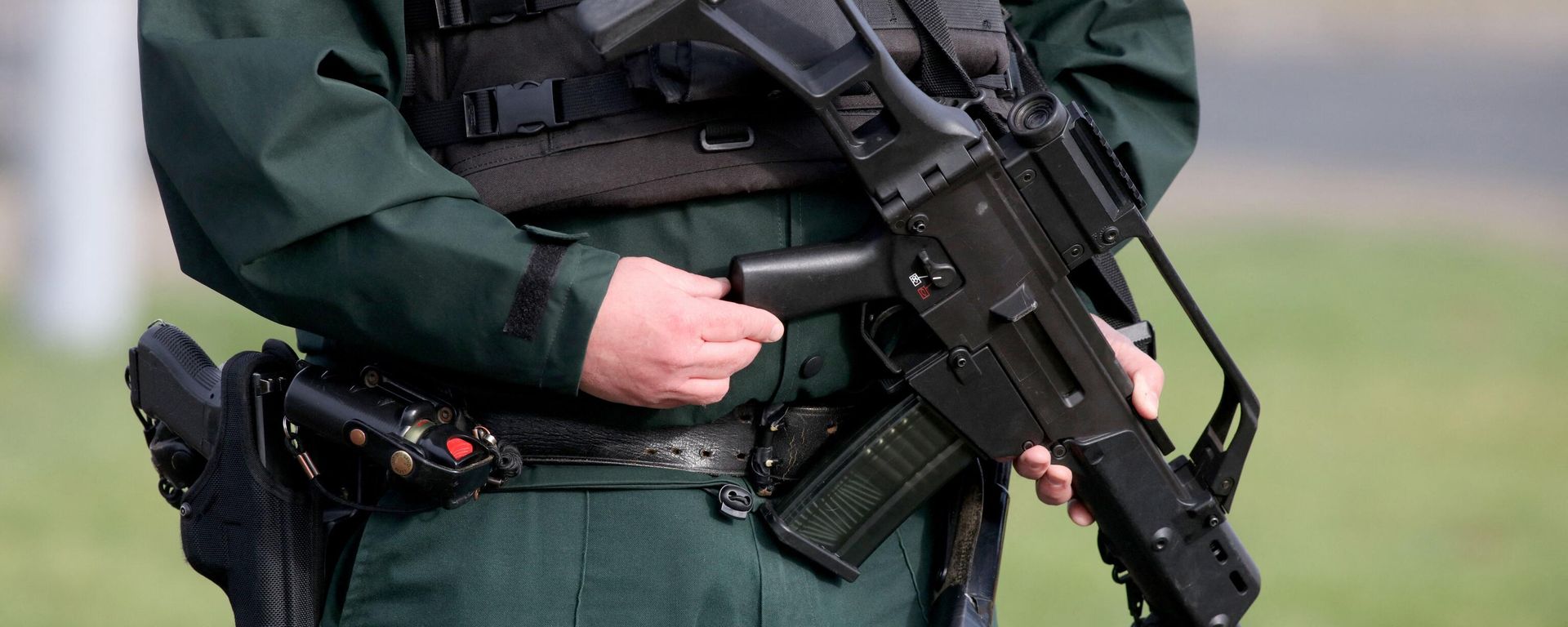 An armed police officer stands guard at the scene of a shooting of an off duty policeman at the Killyclogher Road sports complex in the northern Irish town of Omagh An armed police officer stands guard at the scene of a shooting of an off duty policeman at the Killyclogher Road sports complex in the northern Irish town of Omagh - Sputnik International, 1920, 23.02.2023
